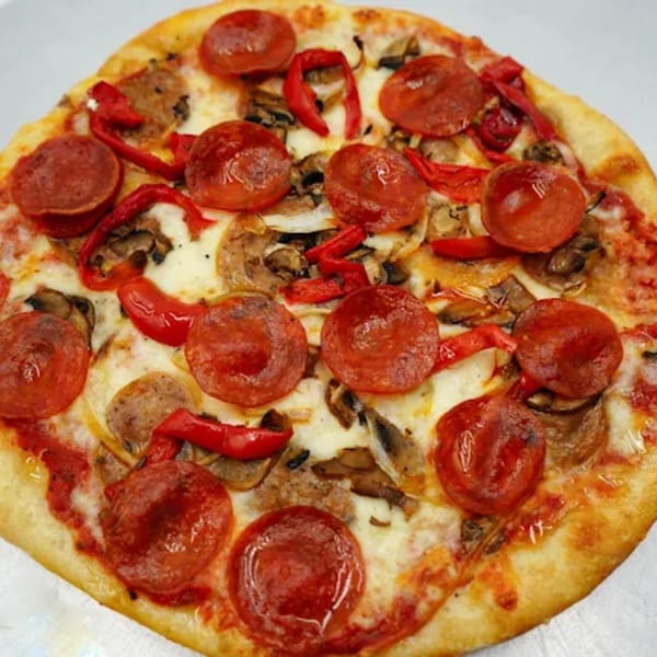 Antonella's pepperoni pizza with red peppers, mushrooms, and sausage on a white background.