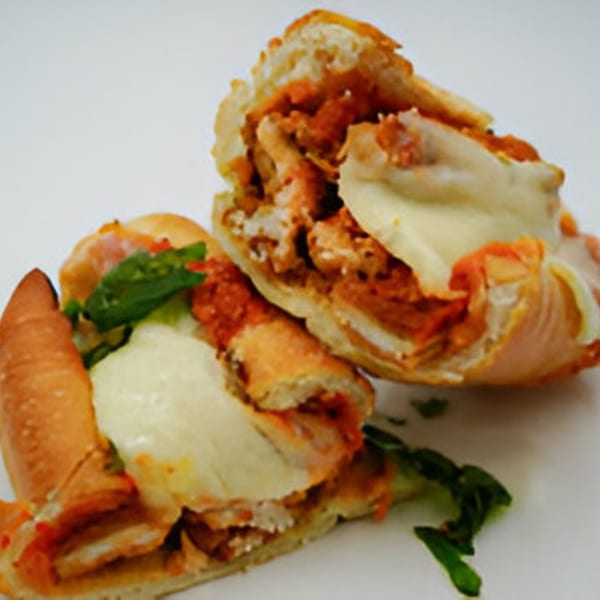 Two halves of a chicken parmesan sub, filled with chicken, marinara, melted mozzarella, and basil.