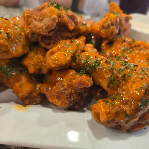 Antonella's Pizzeria's buffalo wings, coated in orange sauce and sprinkled with green herbs.